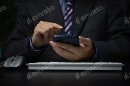 Preview: Business man holding mobile smartphone and keyboard computer on desk.
