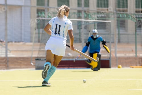 Preview: Female forward attacking the goalkeeper in a field hockey game