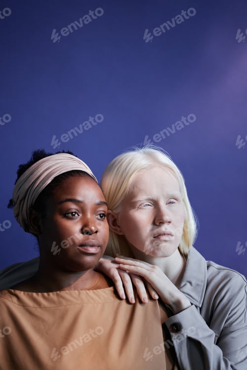Preview: Black and Caucasian Women Standing against Blue Wall