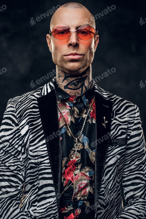 Preview: Calm tattooed, bald fashionable male model posing in a studio for the photoshoot, portrait close up