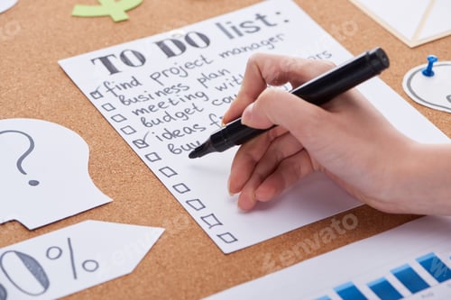 Preview: Cropped View of Woman Writing With Black Highlighter on to do List on Cork Board