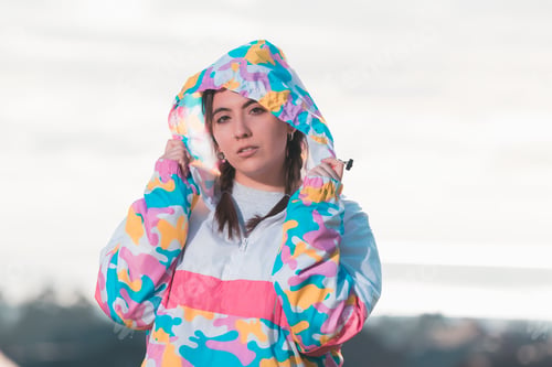 Preview: Shallow focus of a young female with a nose piercing wearing a colorful hoodie outdoors
