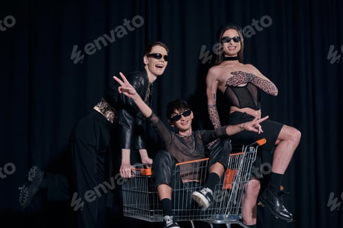 Preview: Smiling and stylish group of homosexual friends in sunglasses having fun with friend in shopping