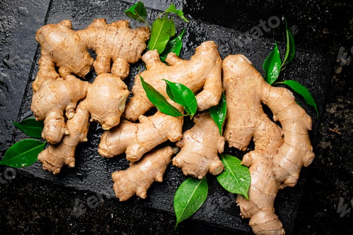 Preview: Fresh ginger with leaves on a stone board.