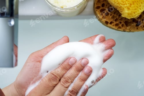 Preview: Foam cleanser in female hands over the sink.