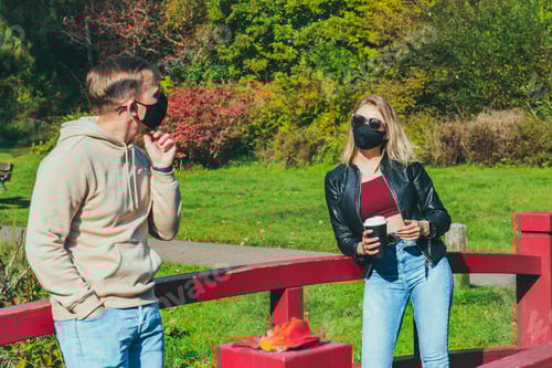 Visualização: Jovens com máscara facial conversando ao ar livre seguindo as regras de distanciamento social.