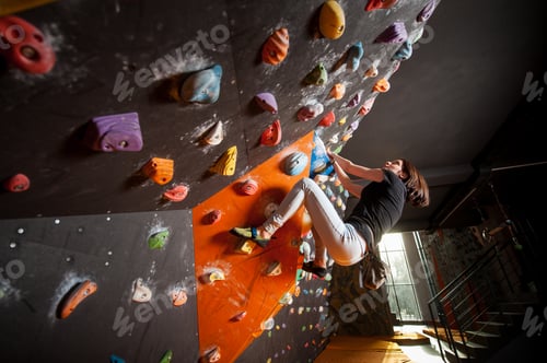 Preview: Strong female climber on boulder climbing wall indoor