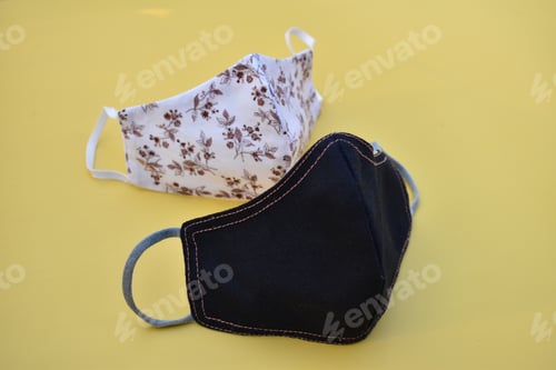 Preview: Protective cloth masks of different colors on a yellow surface