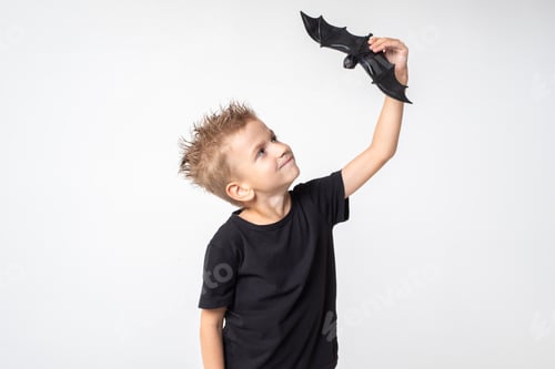Preview: Kids Halloween. A beautiful emotional boy in a black T-shirt holds a bat toy. The boy scares