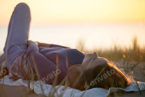 Preview: Calm young woman lying on blanket relaxed enjoy autumn sunset in fall field look at setting sun sky