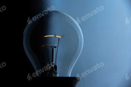 Preview: Illuminated Light Bulb with Glowing Filament on Blue
