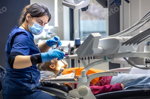 Preview: Young female dentist in dental office. Dentist at work. Dental treatment concept.
