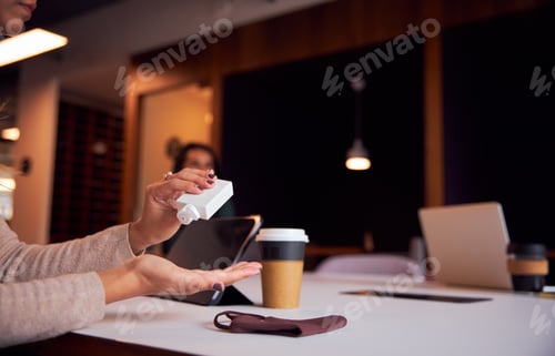 Preview: Businesswoman Using Hand Sanitiser At Socially Distanced Meeting In Office During Health Pandemic