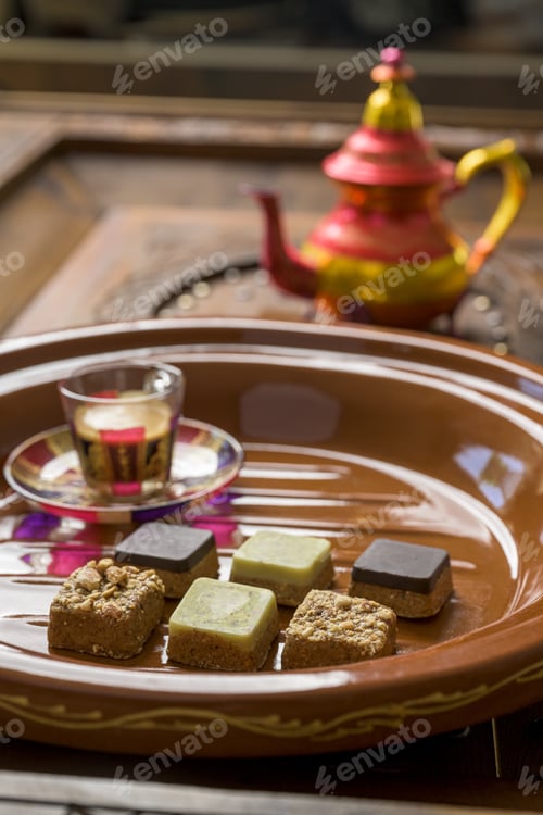 Preview: Closeup shot of different types of square-shaped sweets with tea on a wooden tray