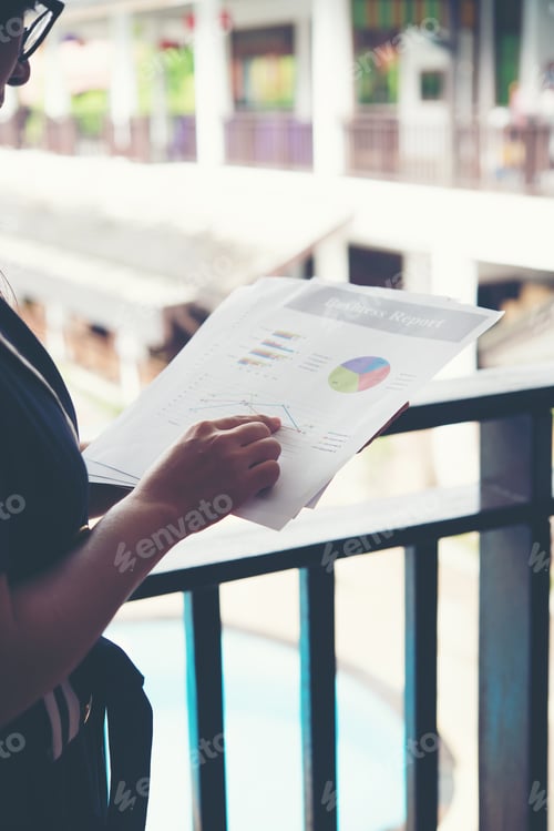 Preview: Hands of financial woman pointing on finance chart notes while working.