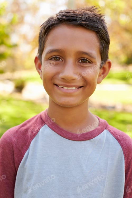 Preview: Smiling mixed race boy in park looking to camera, vertical