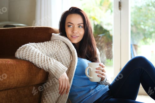 Preview: Young woman sitting floor with cup of tea