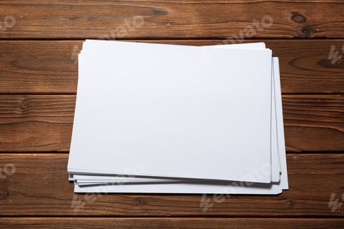 Preview: Blank sheets of paper stacked on a wooden table in a workshop setting during the day