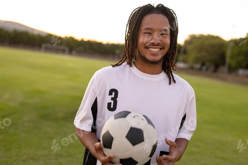 Preview: Man standing on soccer field at sunset, wearing white jersey 3, holding soccer ball, copy space