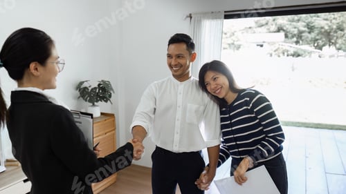 Preview: Young happy smiling couple read agreement with realtor and looking through the contract of real
