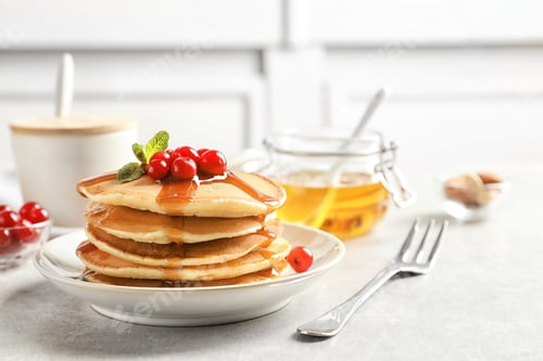 Preview: Stack of tasty pancakes with berries and syrup on table