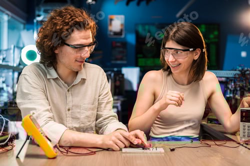 Preview: Young man and woman doing experiments with electricity in a laboratory