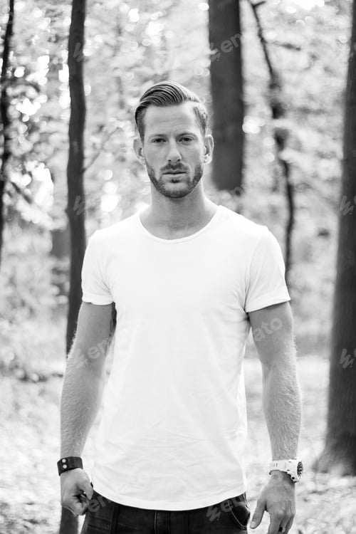 Preview: Vertical grayscale shot of the handsome young man posing outdoors.