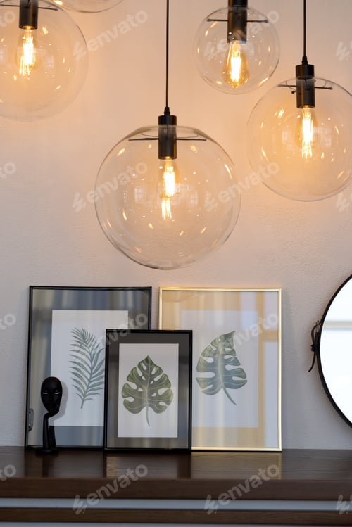 Preview: Four glass transparent hanging round lamps above the table with paintings