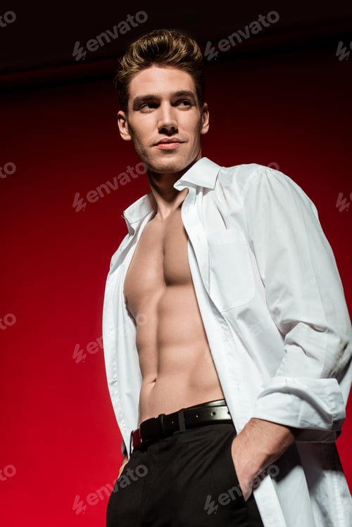 Preview: low angle view of sexy young elegant man in unbuttoned shirt with muscular bare torso posing with