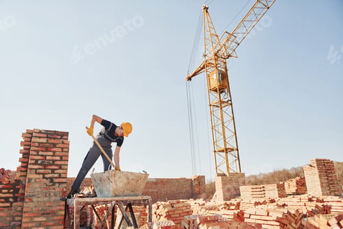 Preview: Using showel. Construction worker in uniform and safety equipment have job on building