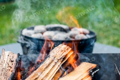 Preview: Cooking in cast iron camp oven with charcoal bbq beads. Camp cooking. Campfire in a fire pit.