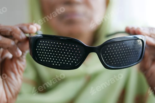 Preview: senior women holding a Perforation glasses with holes for training vision