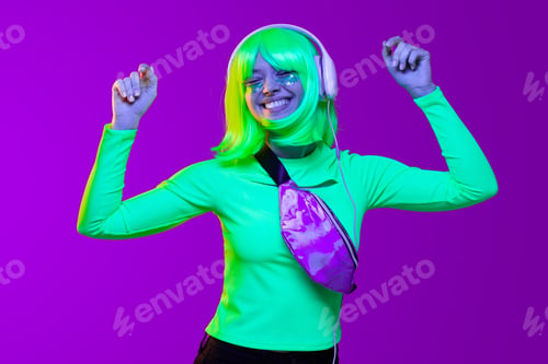 Preview: Young positive teenage girl listening to energetic music in headphones and dancing