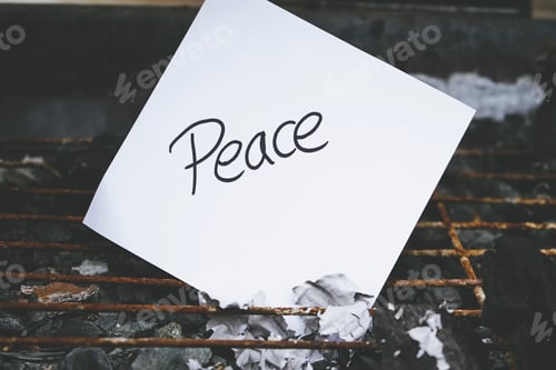 Preview: Word peace writen in a white paper over burned ashes