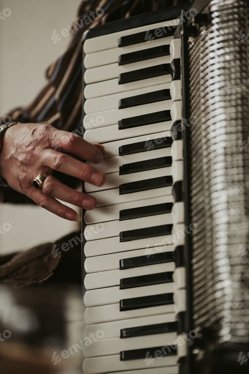Preview: Vertical closeup of an accordion being played by a guy with a golden ring