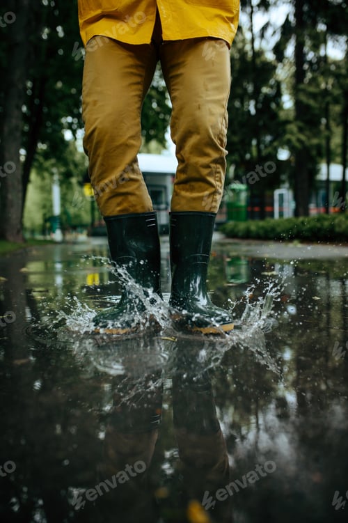 Preview: Male person in rubber boots jumping in puddles