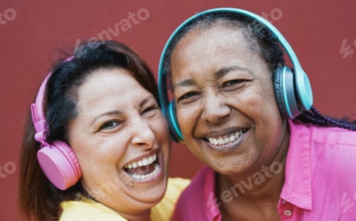 Preview: Multiracial senior women having fun listening music playlist with wireless headphone