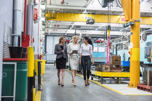 Preview: Three women with tablet walking and talking in factory shop floor