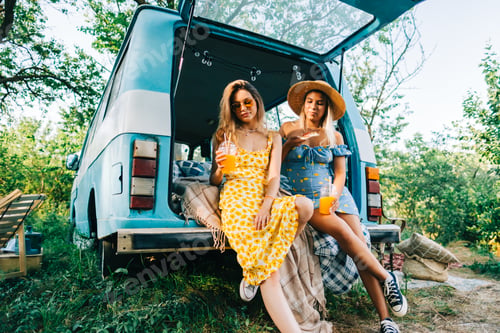 Preview: Two attractive cheerful women drinking lemonade near van and eating pizza
