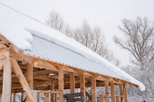 Preview: snow sliding down from roof. building construction house with metal roof covered fresh icy frozen sn