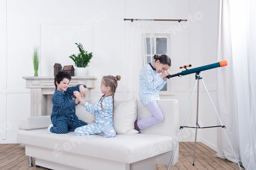 Preview: side view of kids playing with telescope and looking out window