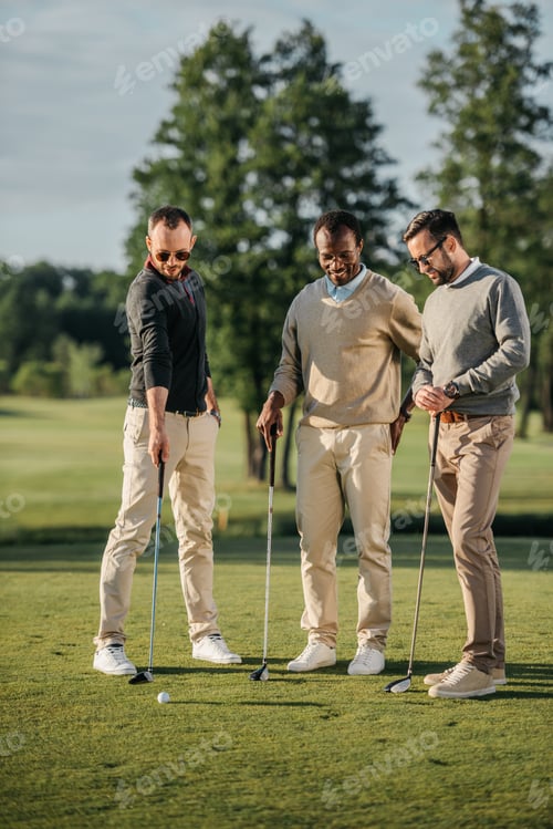 Preview: stylish multiethnic friends spending time together while playing golf on golf course