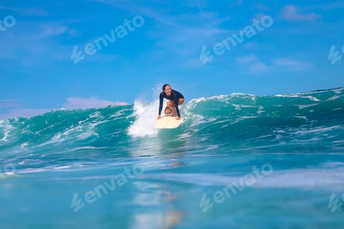 Preview: Female surfer on a blue wave