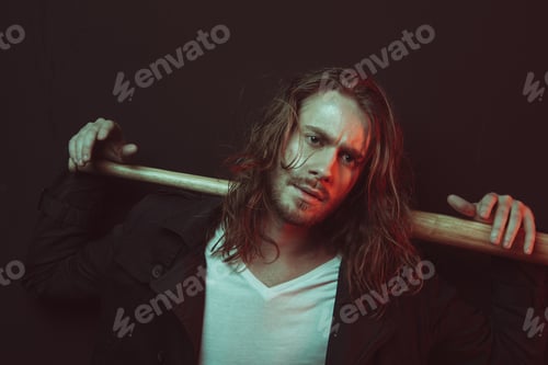 Preview: Portrait of serious stylish long haired man holding baseball bat on shoulders and looking at camera