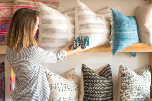 Preview: Rear view of female interior designer trying textile against cushions in retail studio