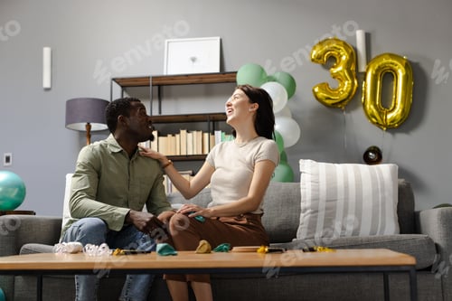 Preview: Couple celebrating 30th birthday at home, smiling and enjoying festive balloons