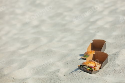 Preview: Tasty burger in box on white sand on beach