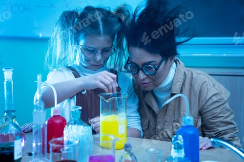 Preview: Teacher and little girl during chemistry lesson mixing chemicals in a laboratory