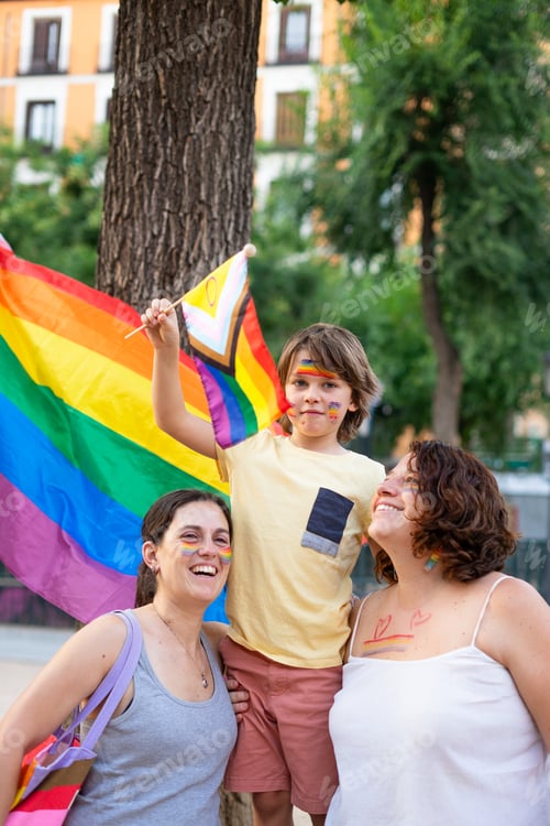Preview: Lesbian family with one child on LGBT pride day with LGBTI flags and rainbow painted face