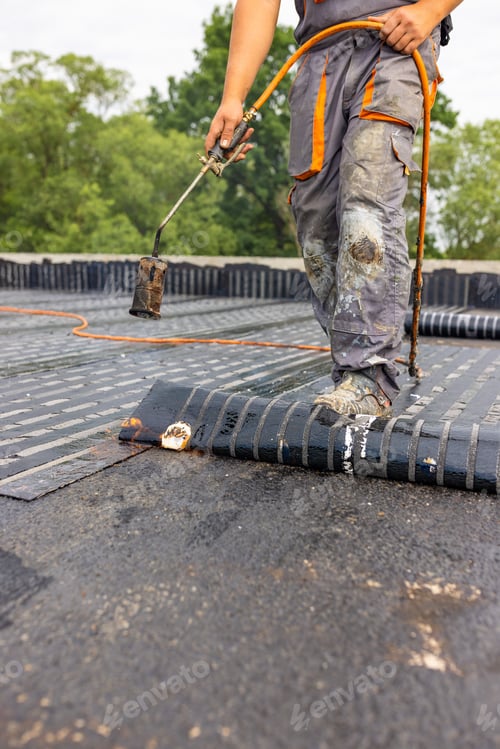 Preview: Worker placing a vapor barrier on the roof using a propane gas torch for welding bitumen sheets